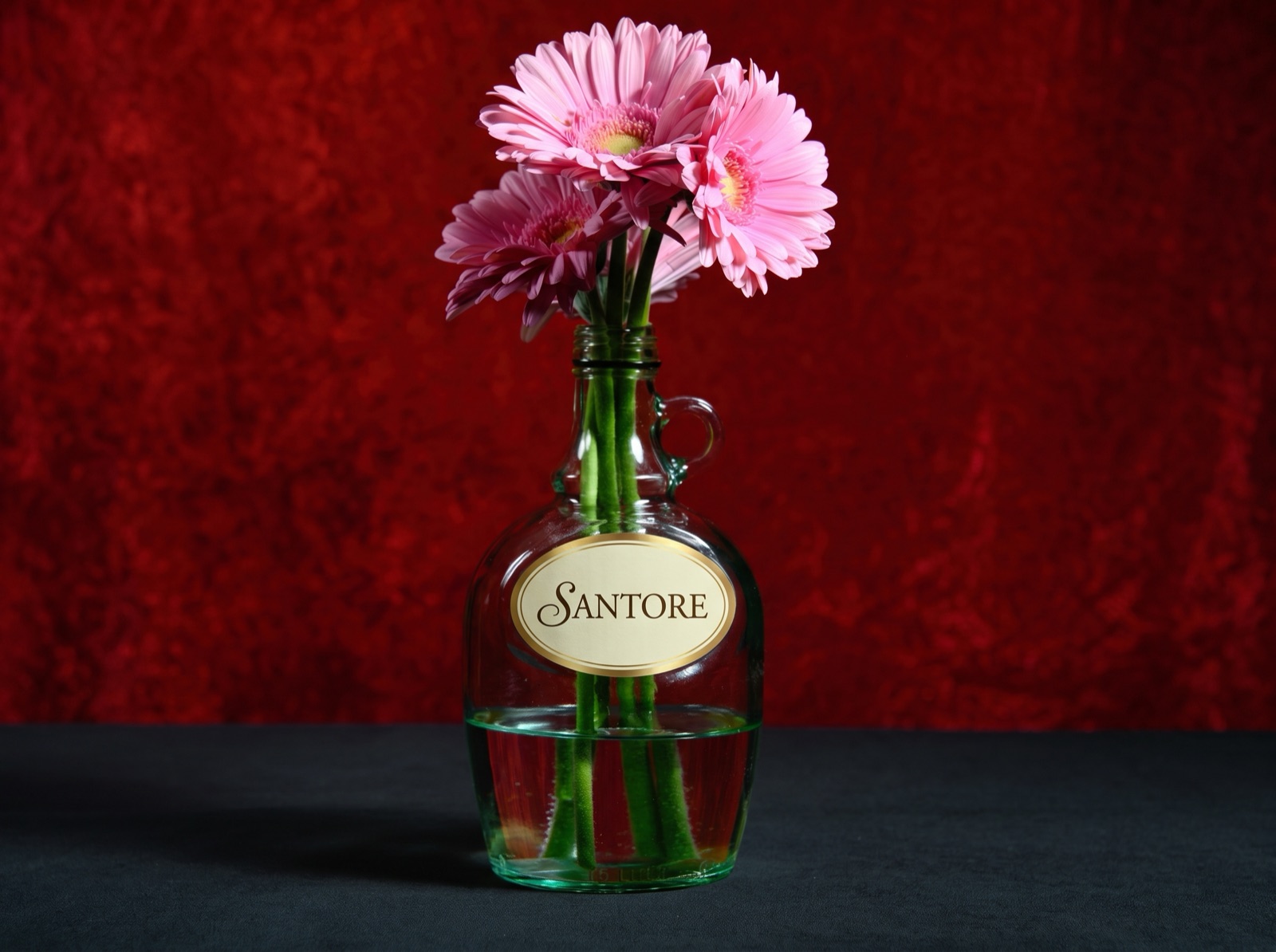 Glass jug with an oval gold-rimmed custom label and flowers