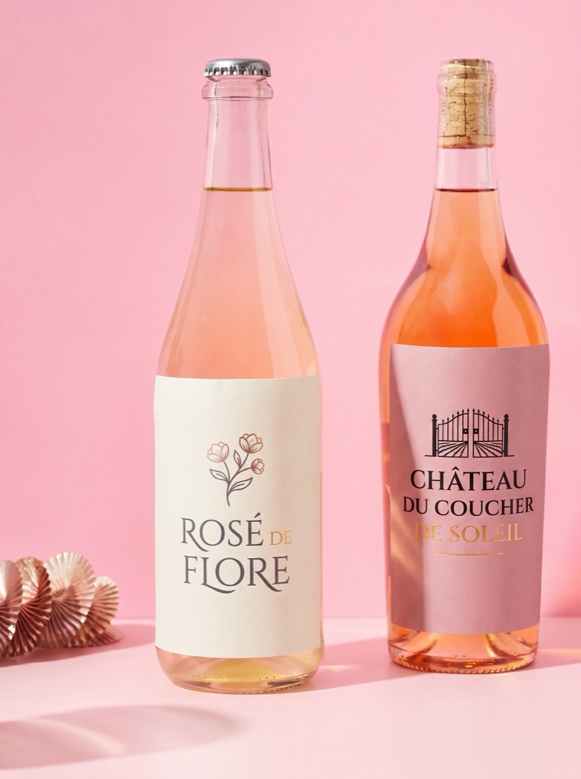 Two rose wine bottles with custom winery labels, pink backdrop